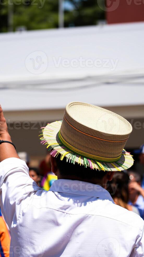 Man wearing a straw hat with colorful fringe in a crowd photo