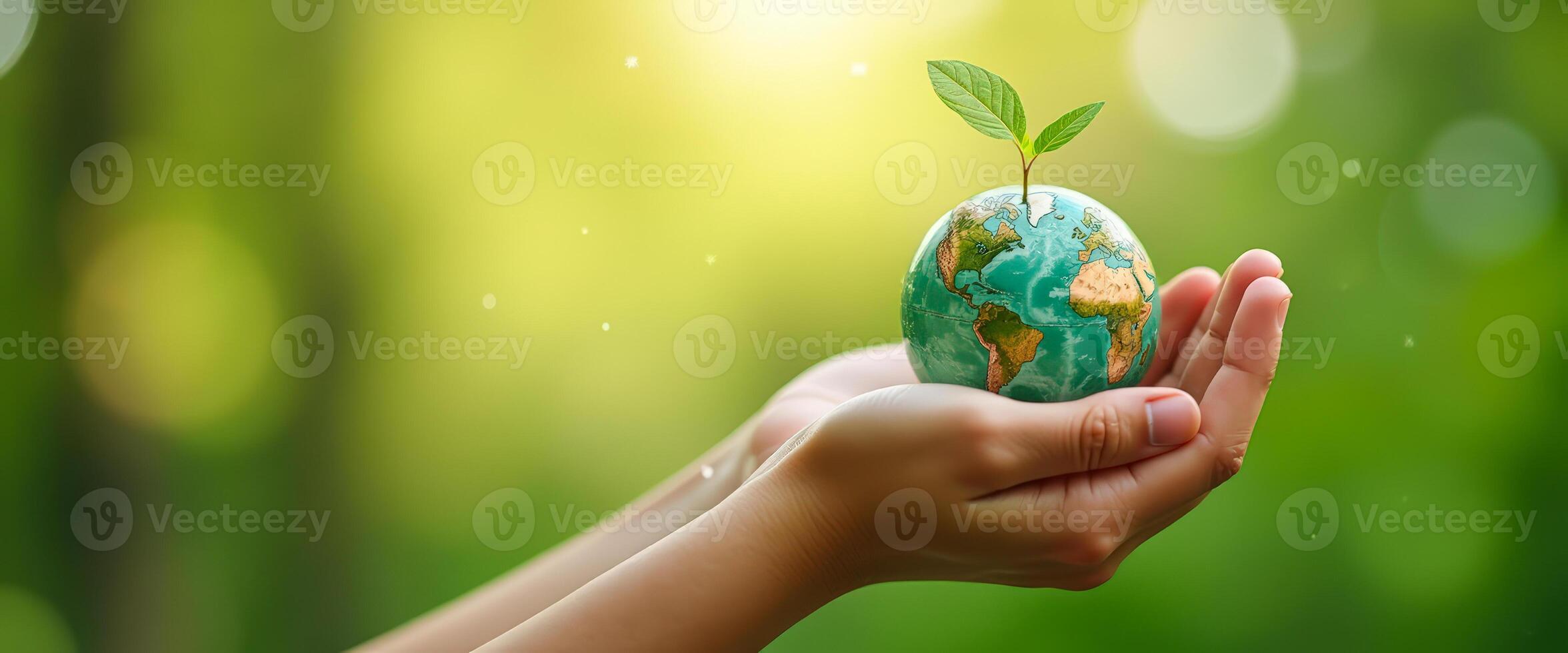 Hands holding a small globe with a sprout growing from the top photo