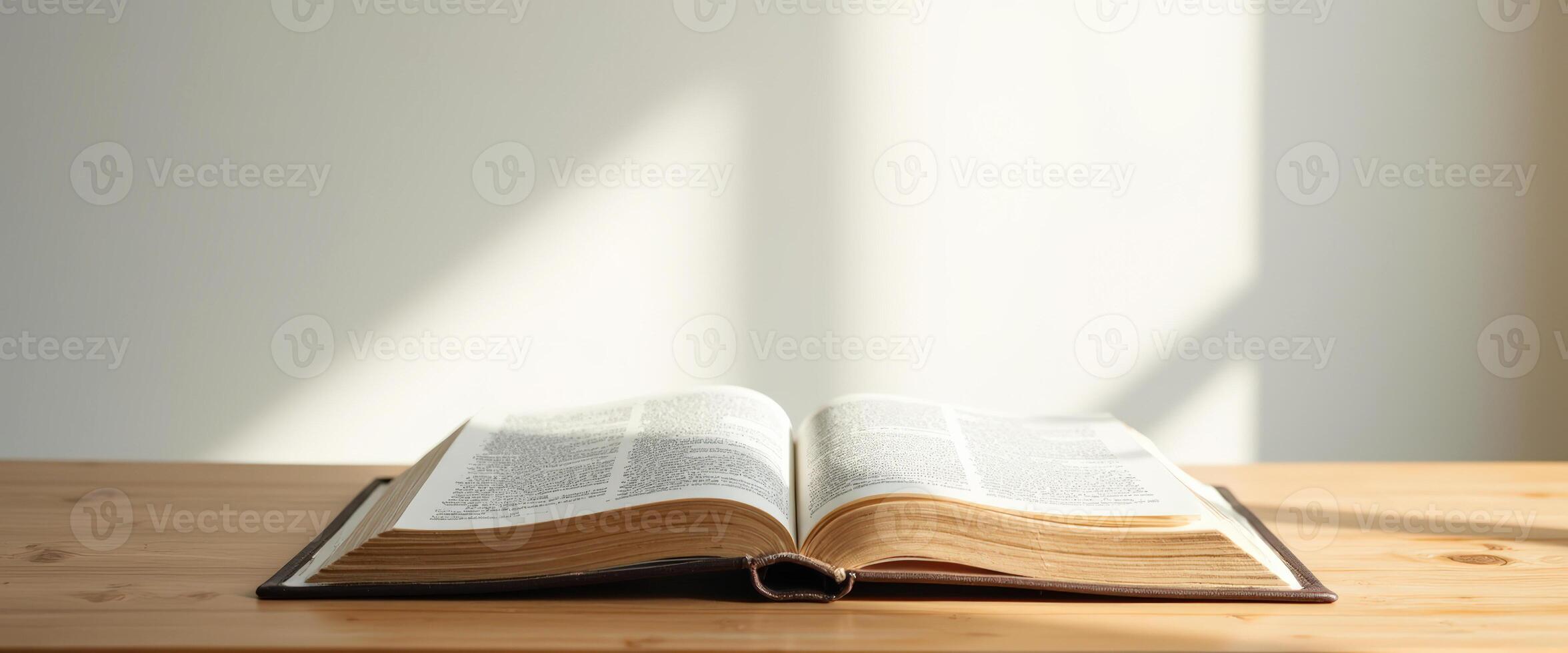 Open book on a wooden table with sunlight streaming in photo