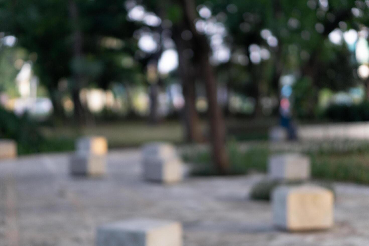 Blurry background of public park outdoors surrounded by trees and sidewalk photo