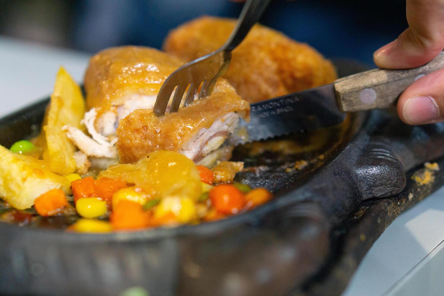Close up of sliced chicken cordon blue with knife and fork on grill plate photo