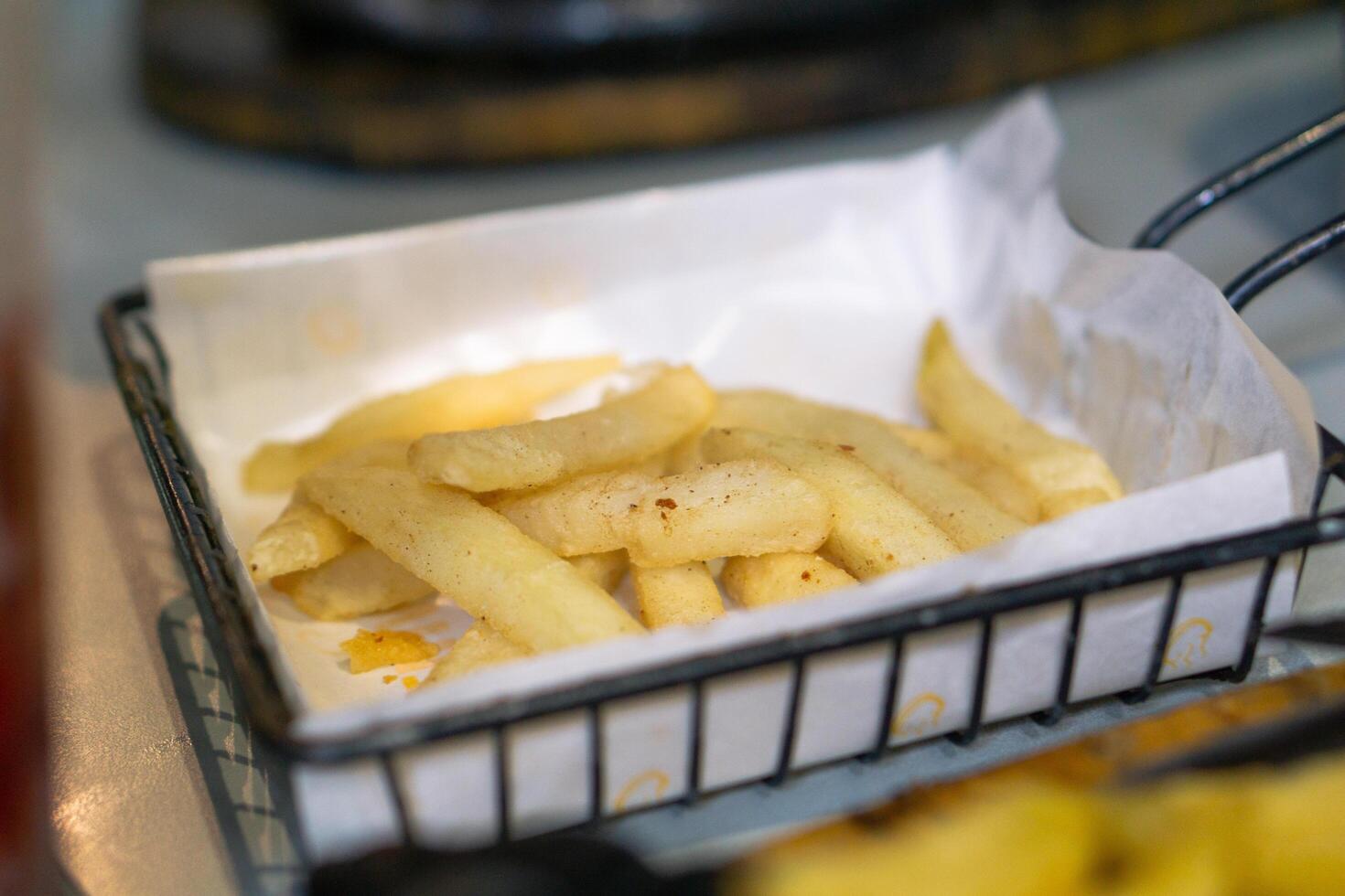 French fries on black basket. Restaurant menu meal. Fast food full of fat and calories photo