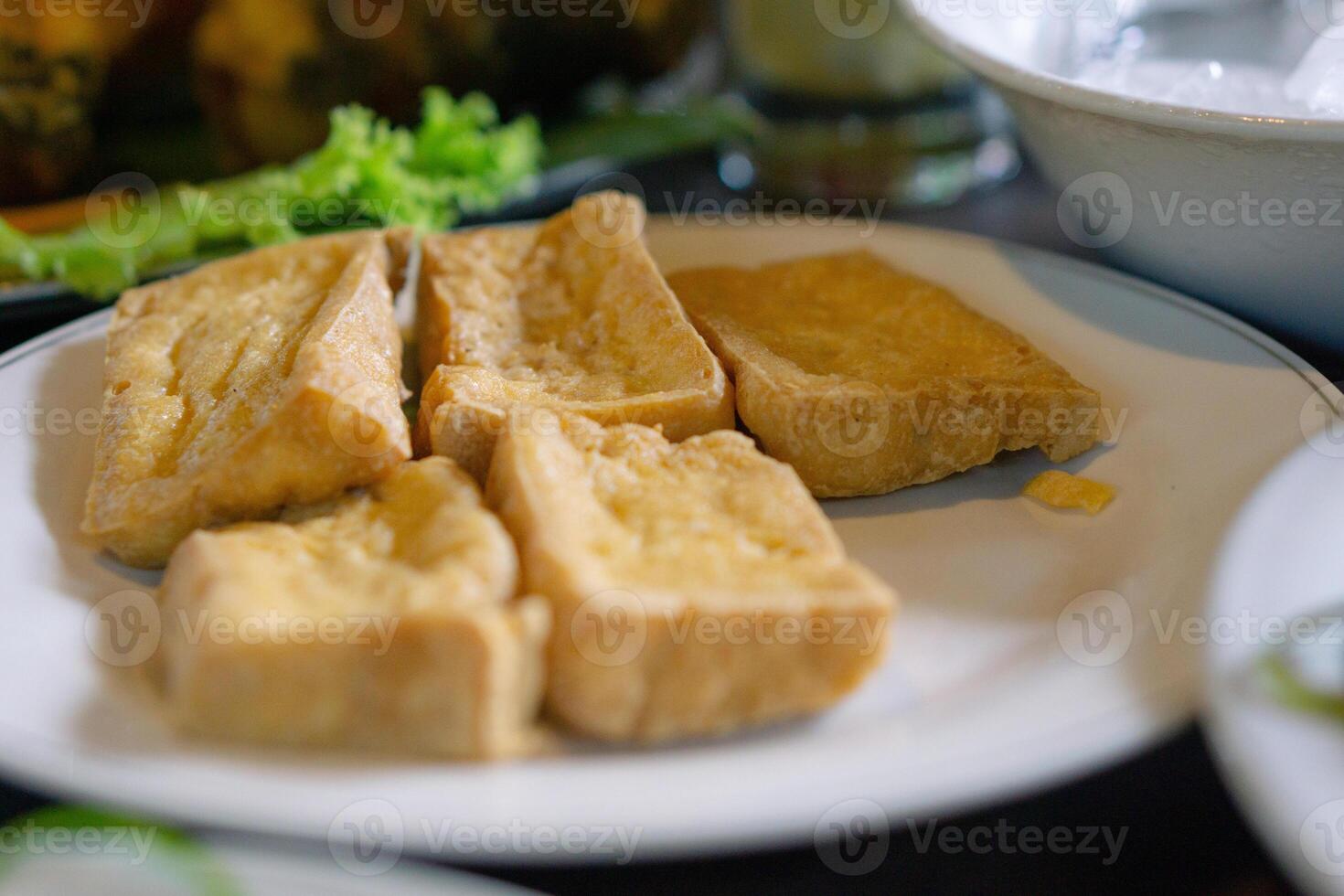 Tahu goreng or fried tofu prepared in white plate. Asian dish and Indonesia local food. photo