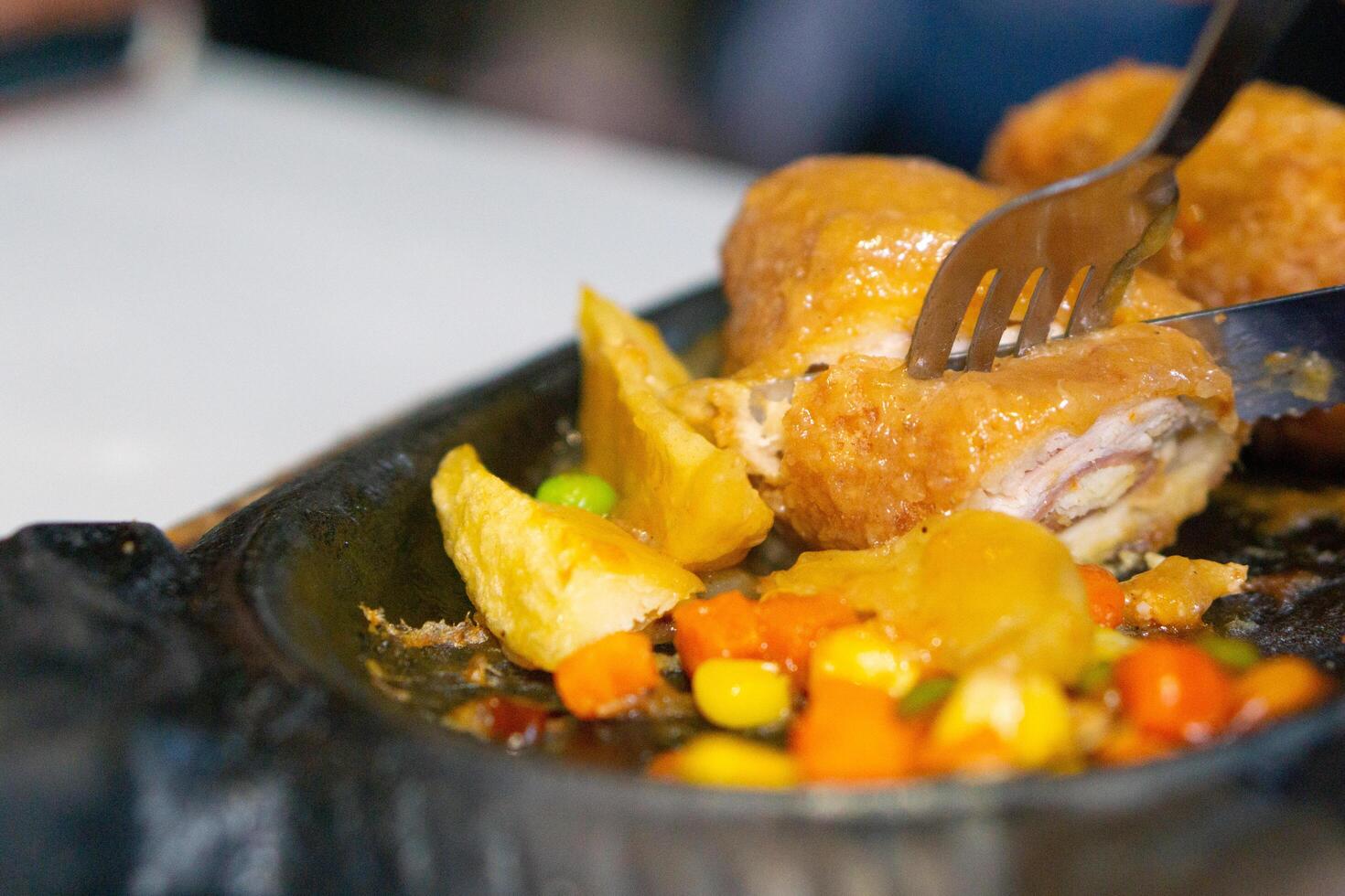Close up of sliced chicken cordon blue with knife and fork on grill plate photo