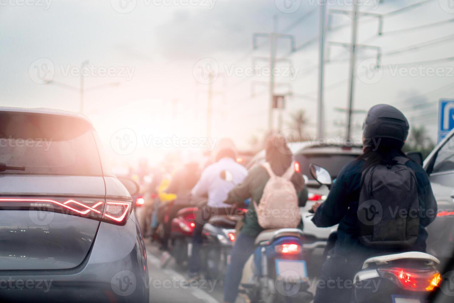 Rear side of luxury grey car with turn on brake light. Beside with many motorcycle and driver. stop and stuck in working time. Environment of air pollution. Beside road with electric pole. photo