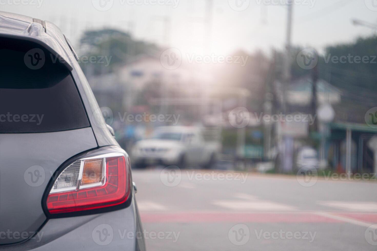 Rear side of grey car on the asphalt road. Front of car on the road with zebra crossing symbol white mix red color. And blurred of the car on opposit road with rural town. photo