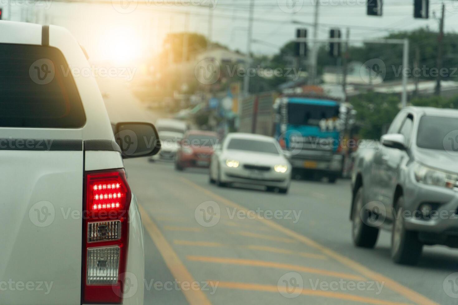 Pickup cars on the road at day. with turn on brake light. cars on the opposite side are driving on the road. Center of road with yellow traffic lines. photo