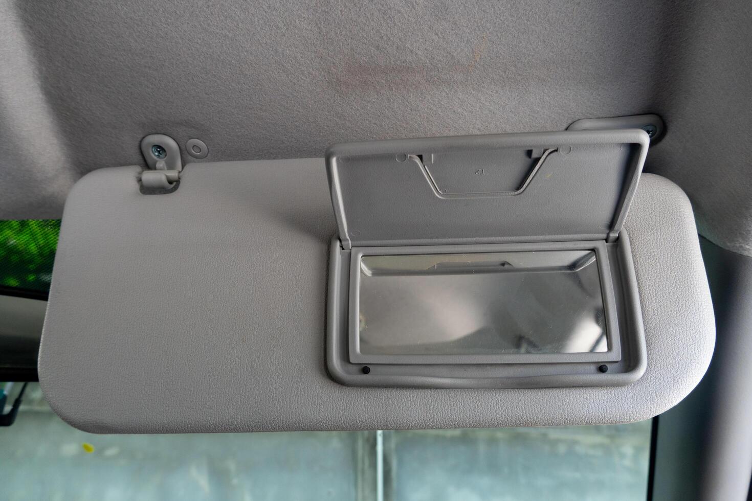 Son visors of car with open close the glass panel. Front view of the driver inside car. Background out of car by cement wall under shadow of tree. photo