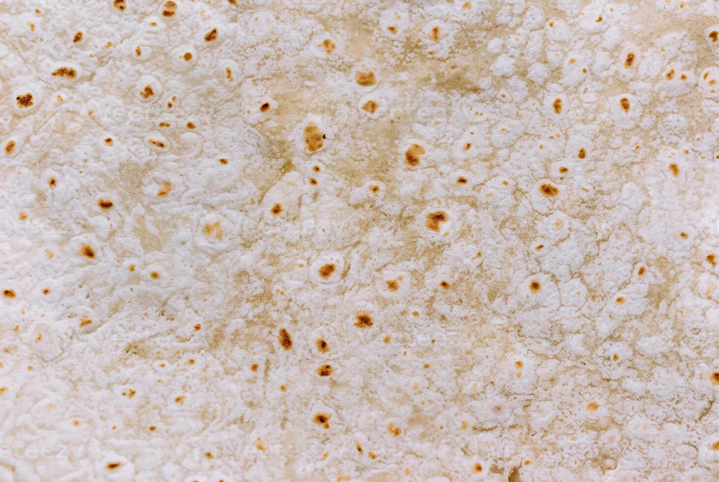 Detailed close-up of a tortilla bread surface showing its unique texture and golden brown spots, perfect for food backgrounds and culinary projects. photo