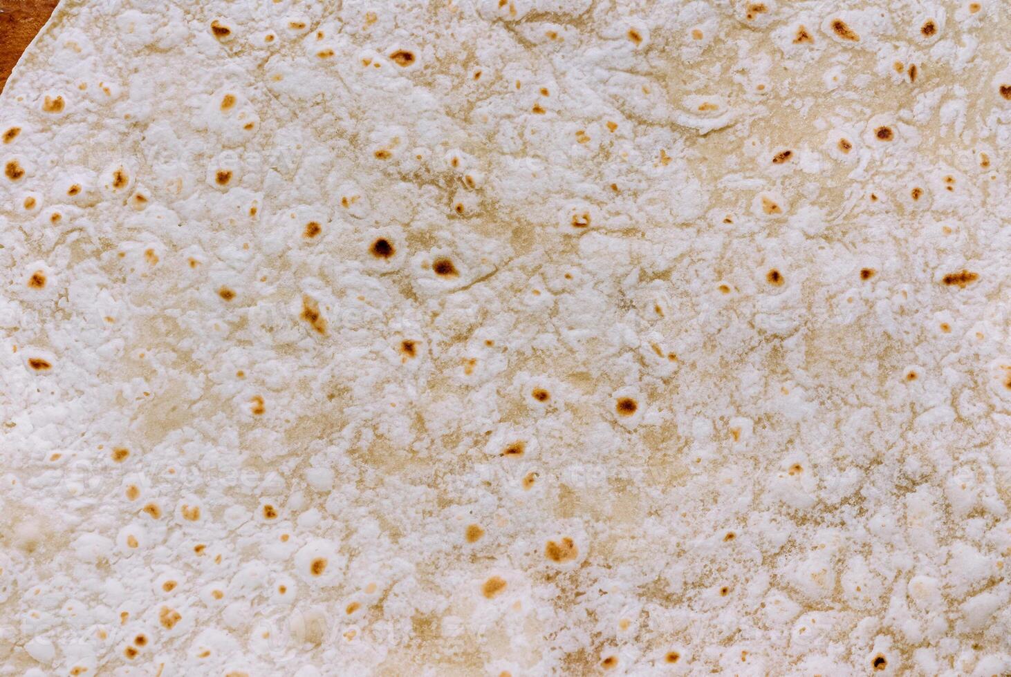 Detailed close-up of a tortilla bread surface showing its unique texture and golden brown spots, perfect for food backgrounds and culinary projects. photo