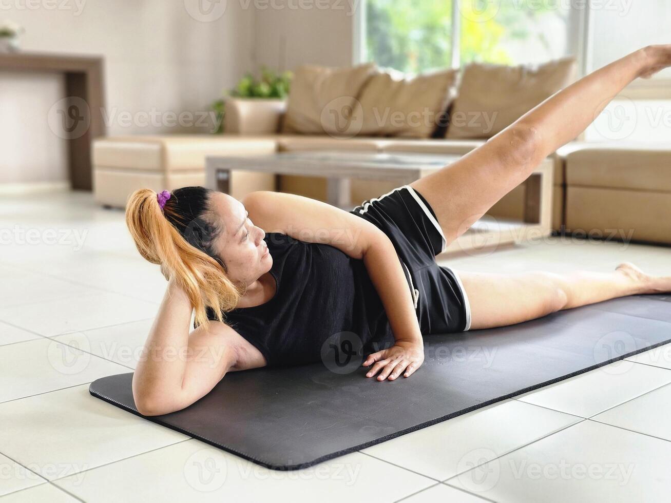 Young Asian woman exercising with side lying leg abduction workout at home patio. wellness concept photo