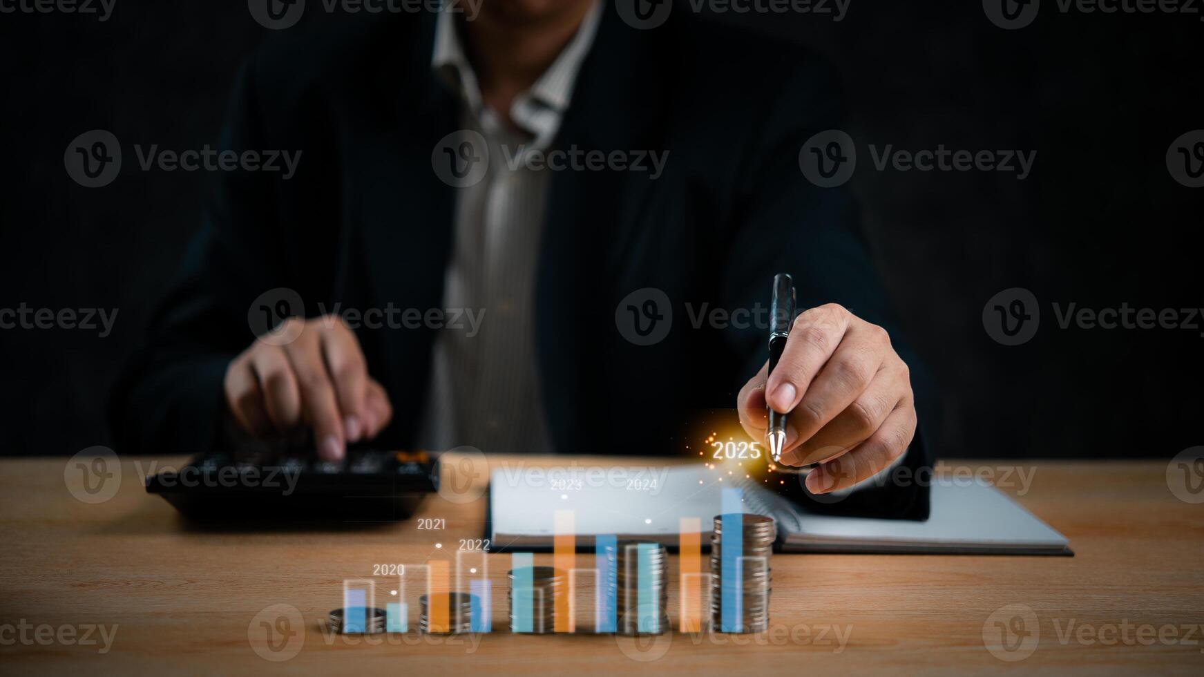 Businessman using calculator and pen to draw graphs on table photo