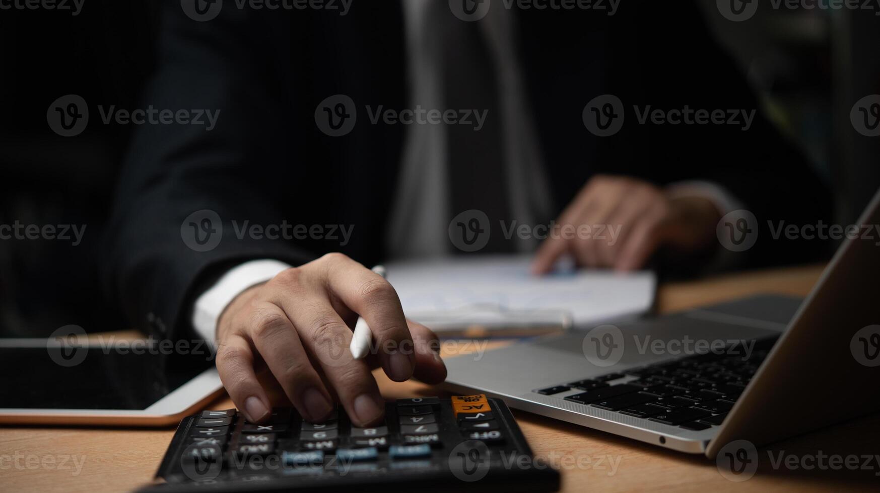Businessman using calculator, writing on paperwork. Financial analysis, accounting, Ideal for finance, accounting, business management visuals. Professional atmosphere. photo