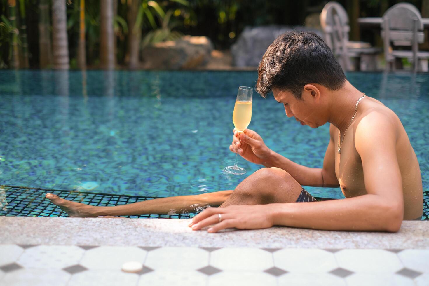 A man has a rest in the pool and enjoying glass of tasty cold white wine during vacation. Travel vacation. Summer holidays. photo