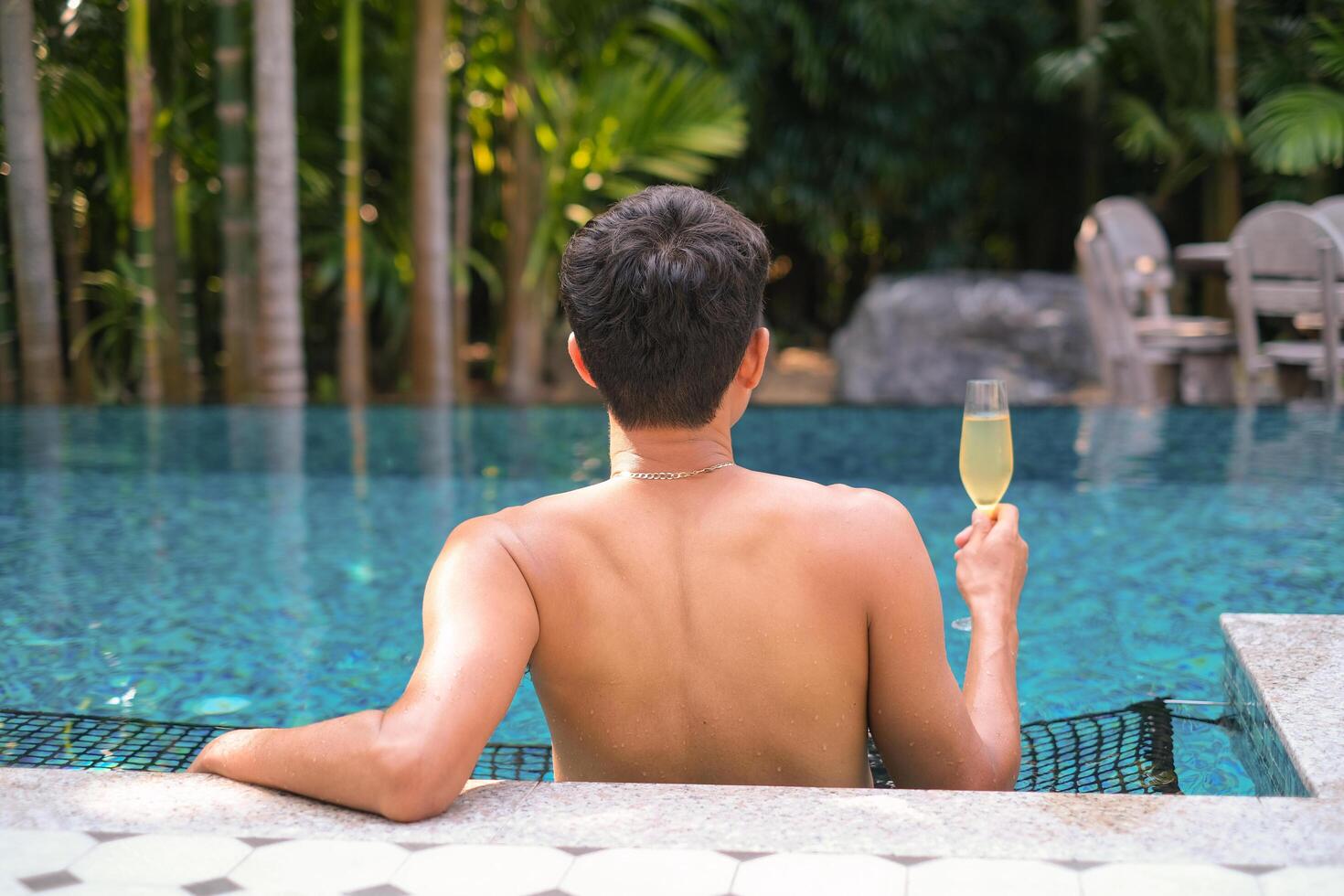 A man has a rest in the pool and enjoying glass of tasty cold white wine during vacation. Travel vacation. Summer holidays. photo