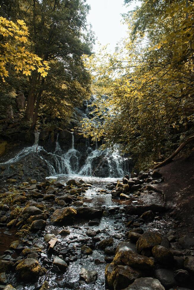 Small waterfall in Sweden in autumn. Moss-covered stones. Forest on the riverbank photo