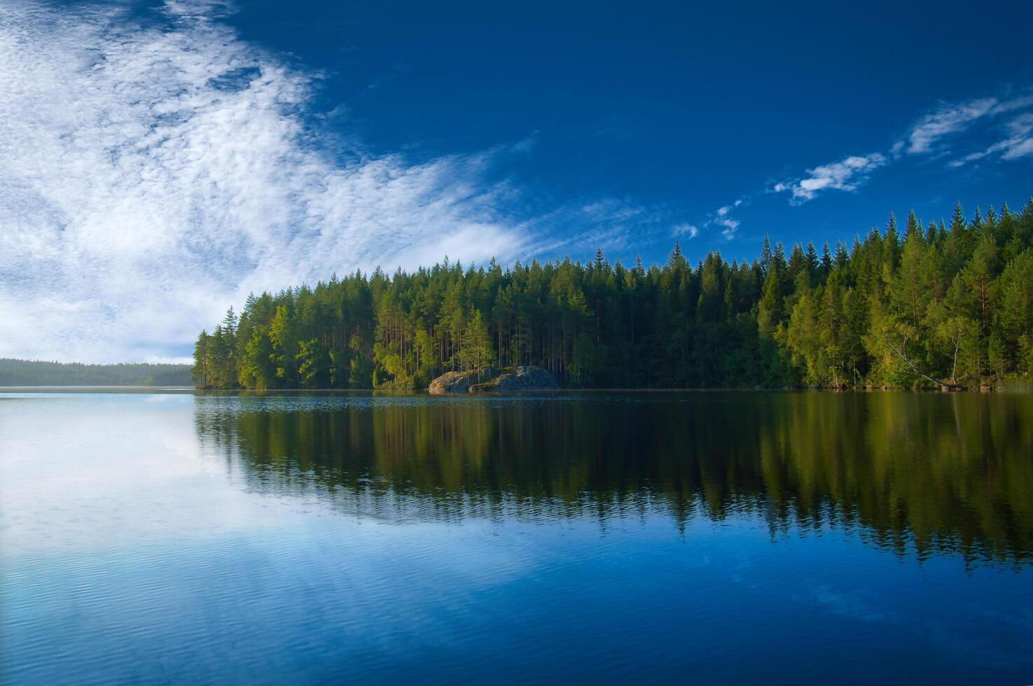 Lake in Sweden with white clouds, blue water and trees on the shore. Scandinavian photo