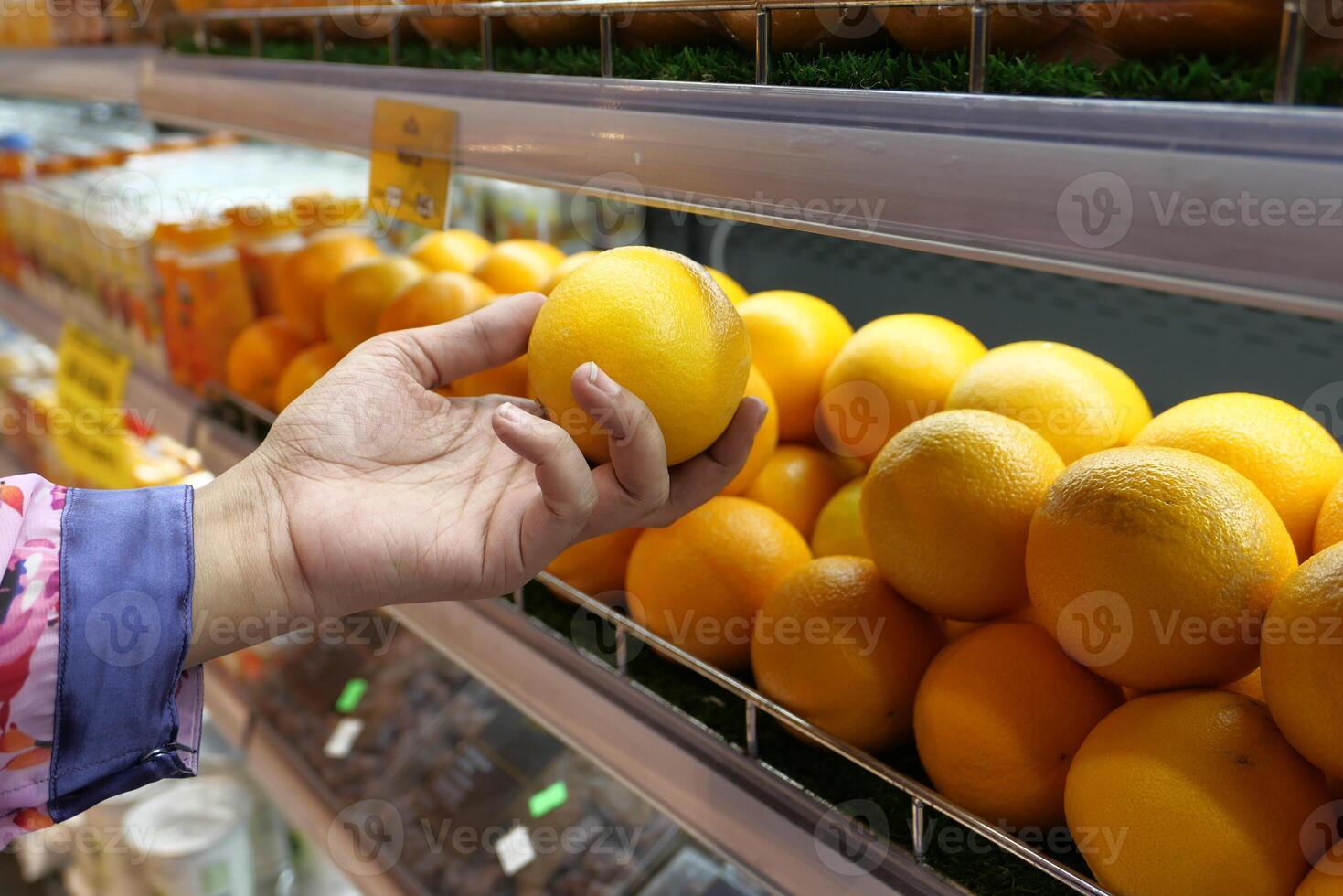 Hand Picking Fresh Oranges Directly from the Supermarket Shelf for Your Enjoyment photo