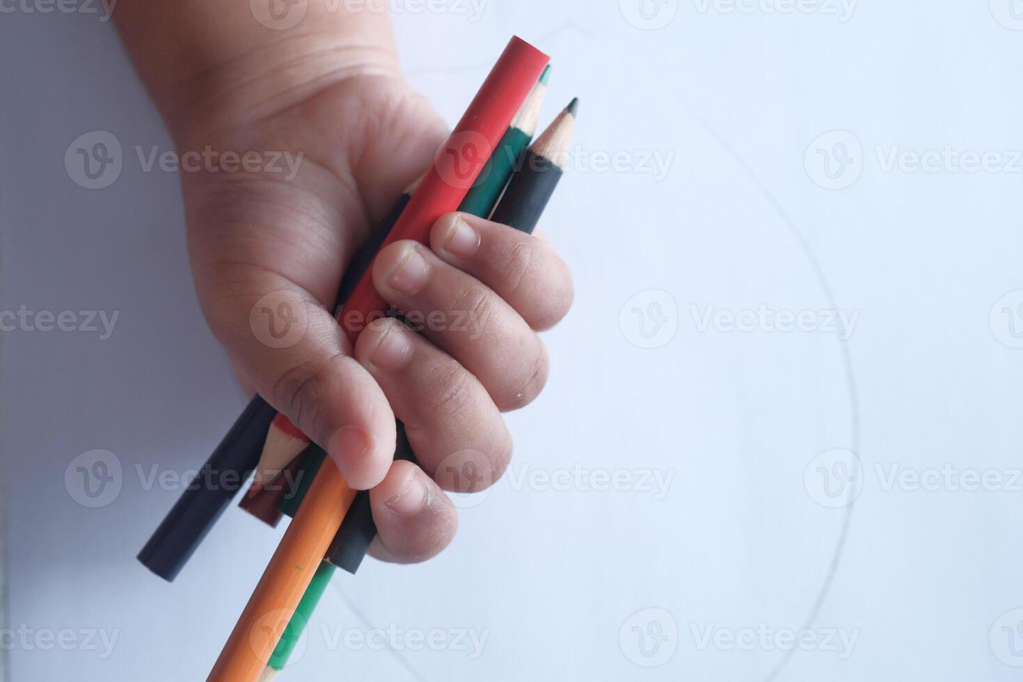 A Childs Small Hand Gently Holding a Set of Colorful Pencils for Art and Creativity photo