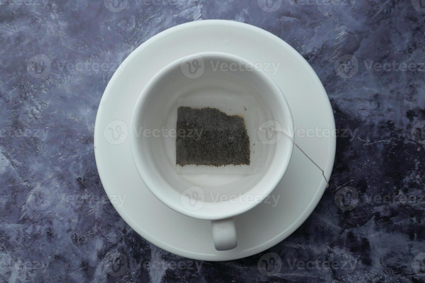 A tea bag is steeping in a white ceramic cup that is elegantly placed on a beautiful marble surface photo