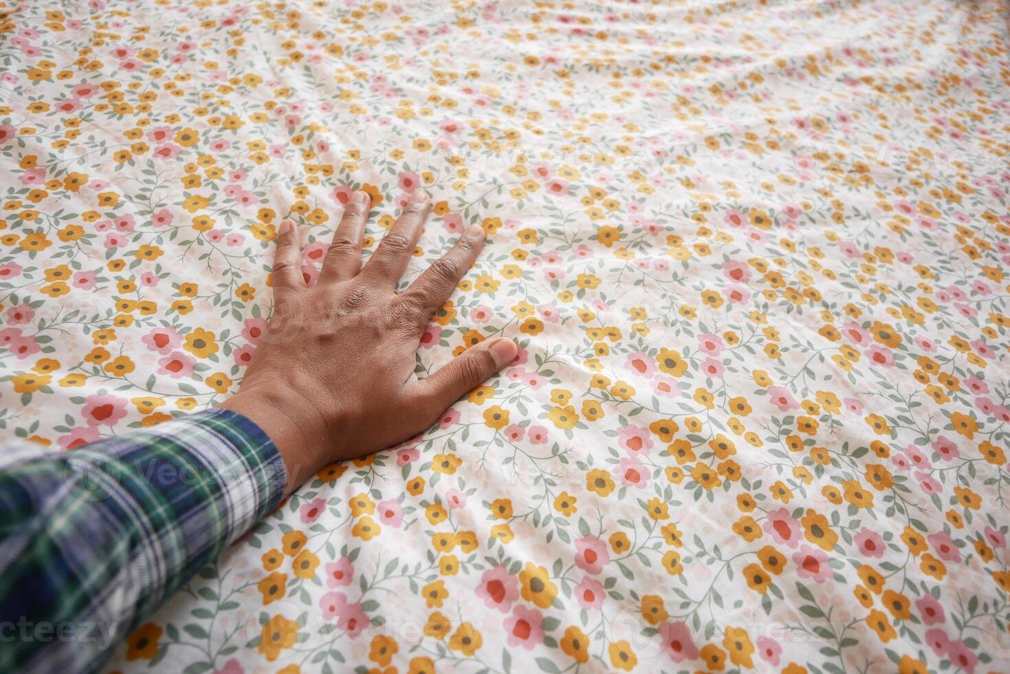 A hand resting gently on a beautifully floral patterned fabric with vibrant and colorful designs photo