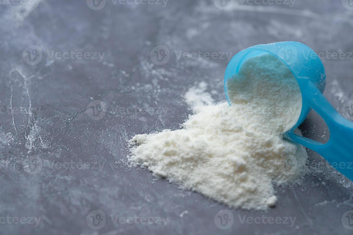 Measuring Flour with a Blue Scoop on a Gray Surface for Culinary Purposes and Baking Needs photo