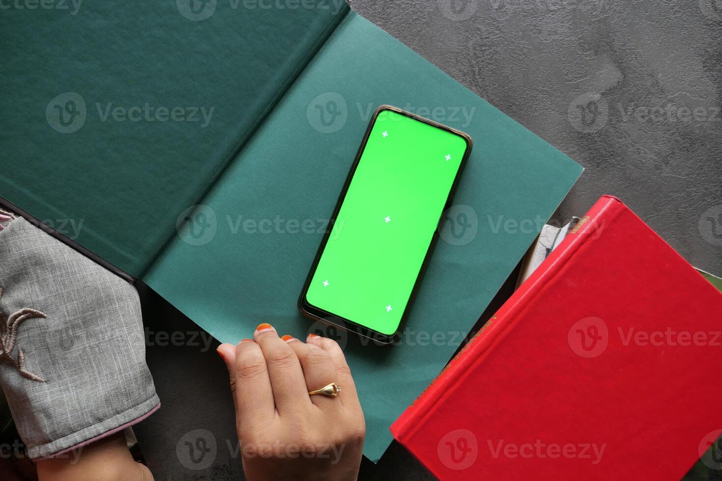 A smartphone placed atop books, set against a vibrant green background designed for creative mockups photo