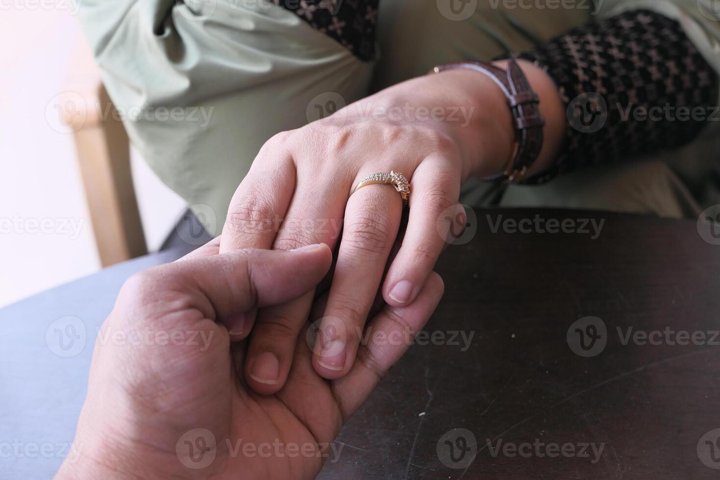 An intimate Romantic Hand Hold adorned with a Wedding Ring in a charming Cafe Setting photo