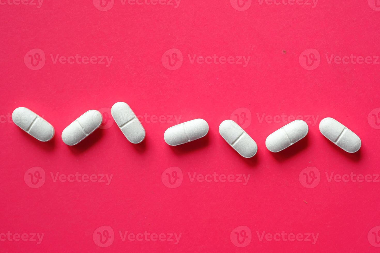 An Array of White Capsules Neatly Arranged Against a Bright and Vibrant Pink Background photo