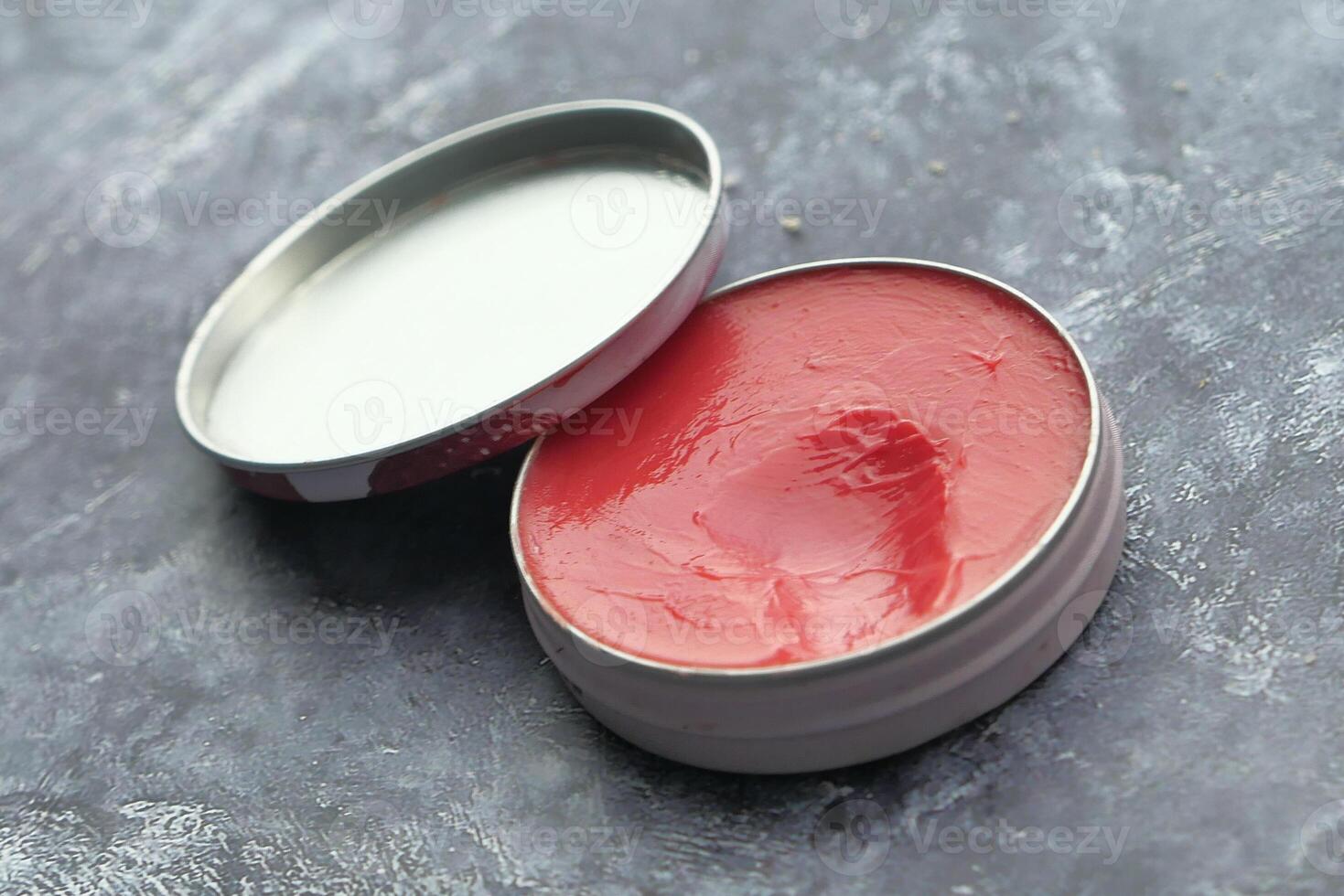An Open Tin of Vibrant Red and White Ointment Placed Elegantly on a Gray Background Surface photo