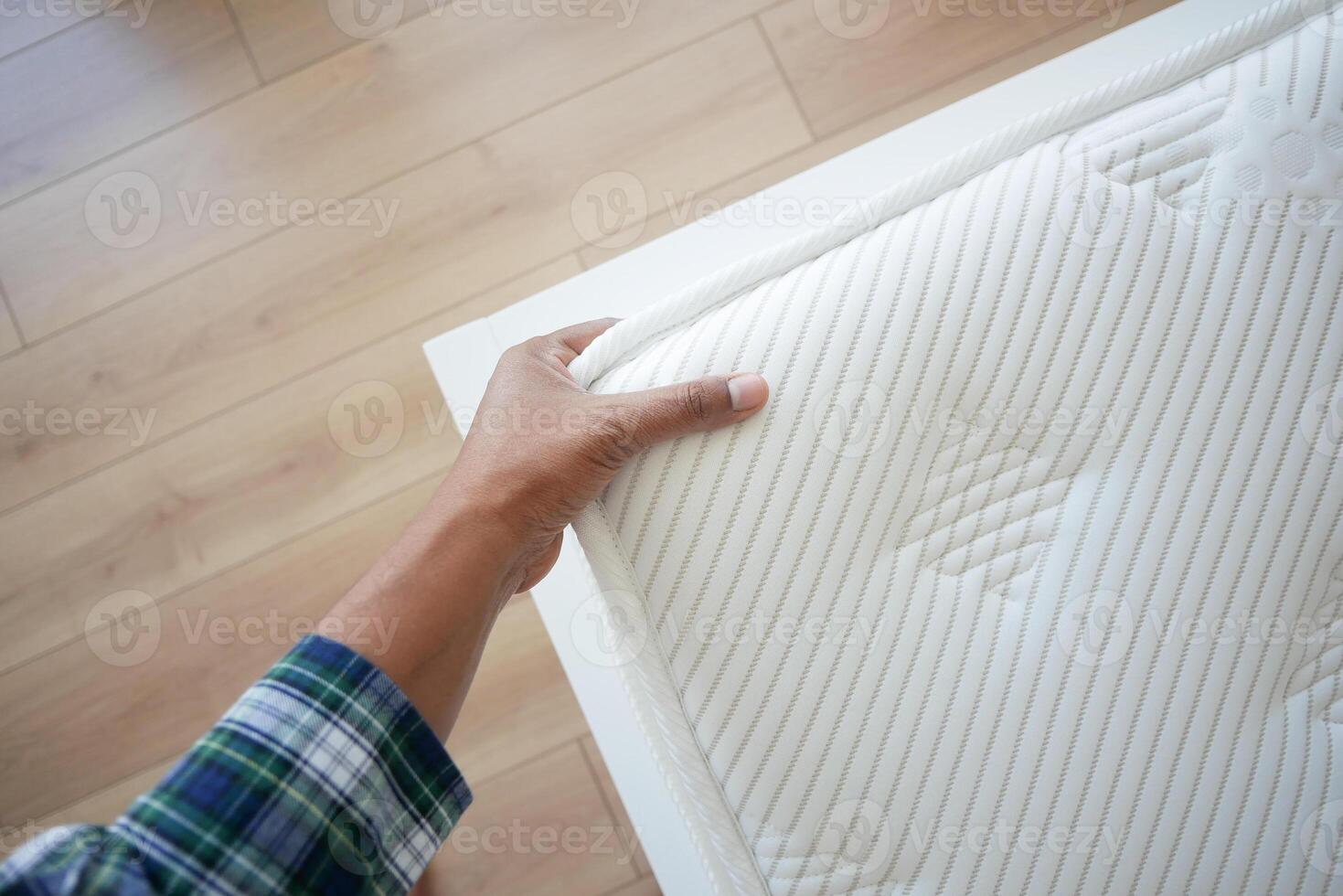 Hand touching and pressing orthopedic mattress on bed. photo