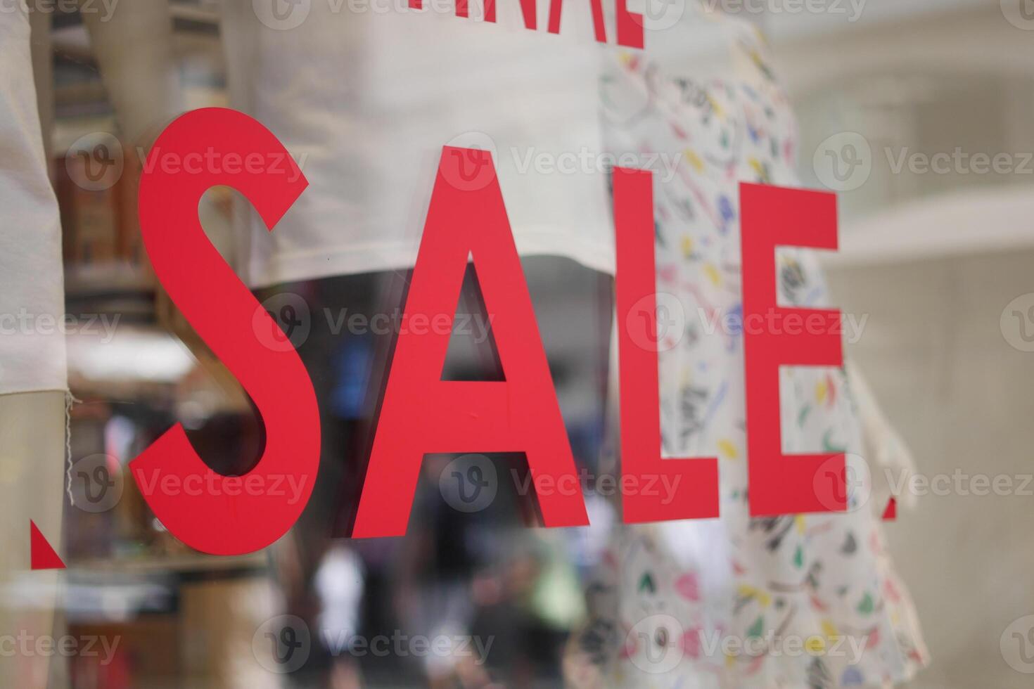 Large red Sale text letters on a glass wall obstruct a view inside the popular fashion store photo