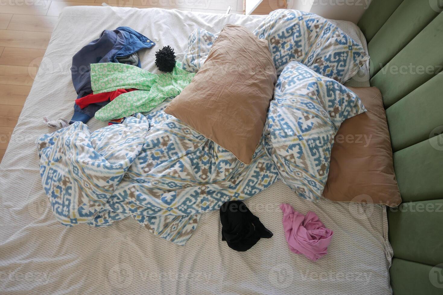 A Messy Bed with Various Colorful Clothes and Soft Pillows Is a Cozy and Casual Space photo