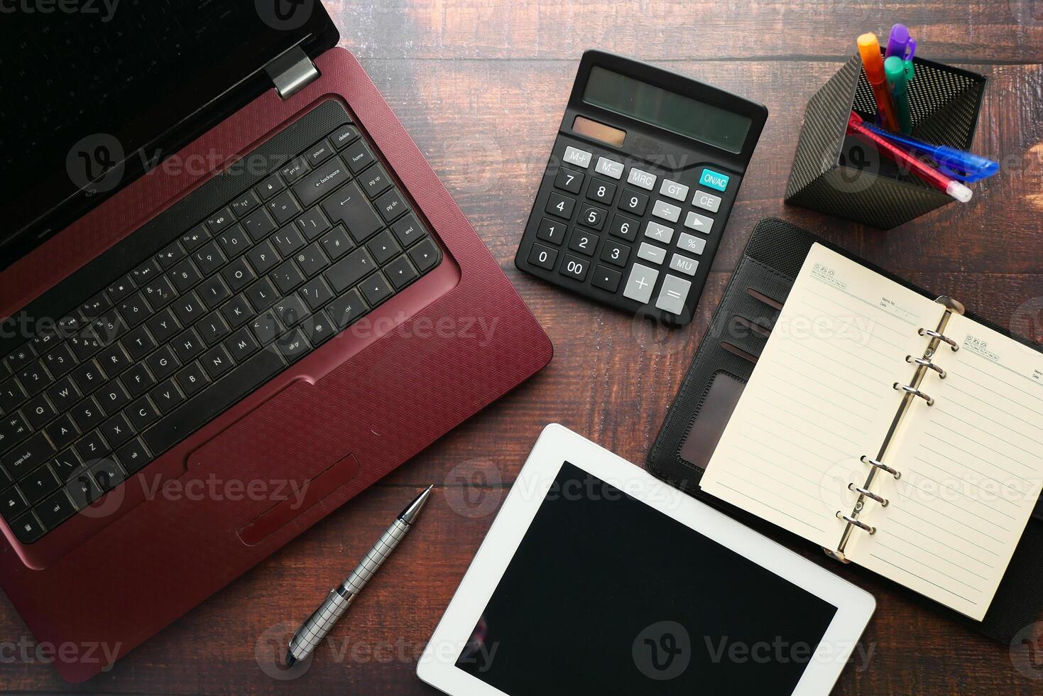 A modern office workspace featuring a laptop, tablet, calculator, and a notepad for tasks photo