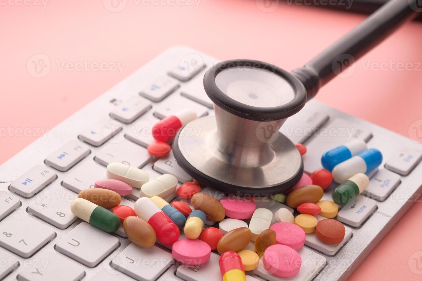 A stethoscope and some pills resting on a computer keyboard illustrate a health concept photo