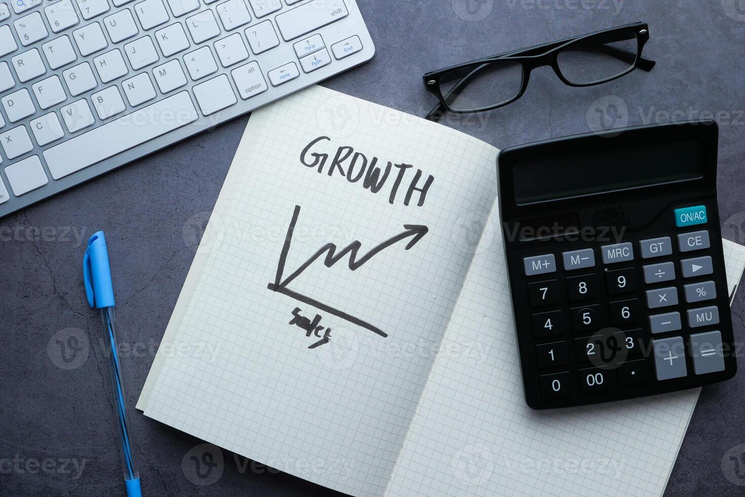 The concept of business growth is illustrated with the use of a calculator and a notebook photo
