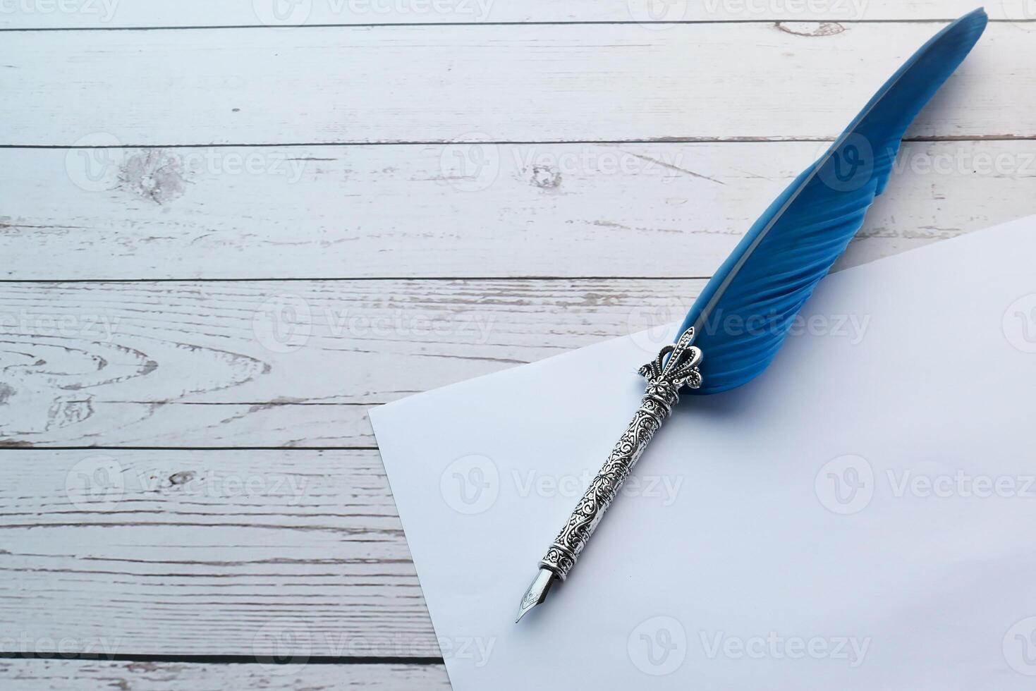 A Blue Feather Quill Pen rests on Blank Paper, inviting creativity and inspiration photo