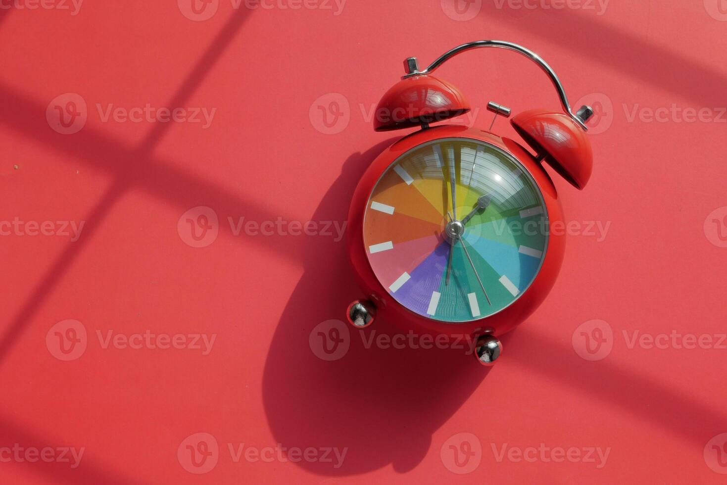 Vibrant and Colorful Alarm Clock Set Against a Bright, Bold Red Background for Display photo
