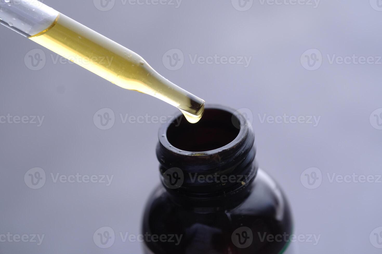 A dropper is used for dispensing oil from a dark glass bottle, which is ideal for storage photo