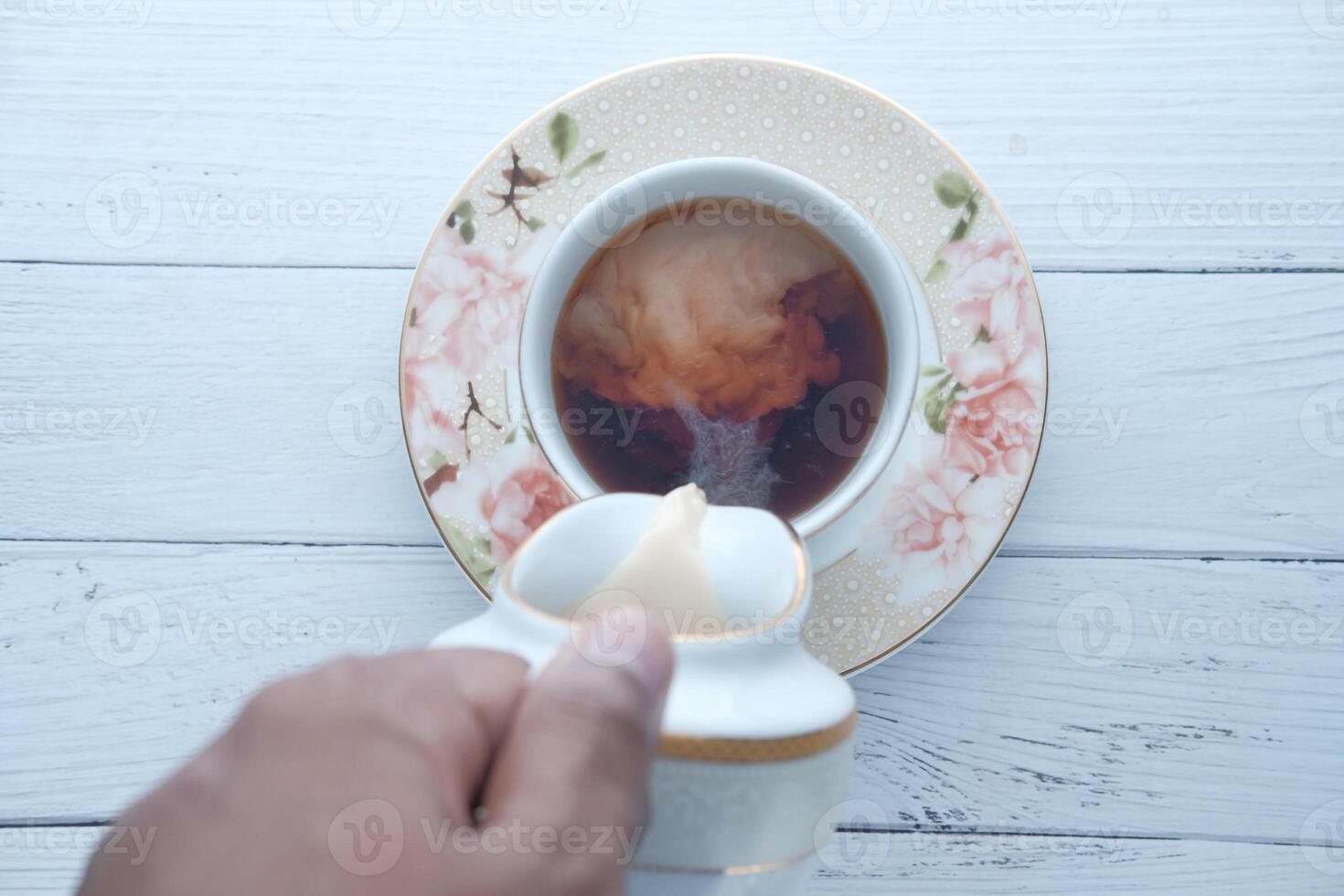 Im pouring creamy goodness into a hot cup of fresh brewed coffee for enjoyment photo