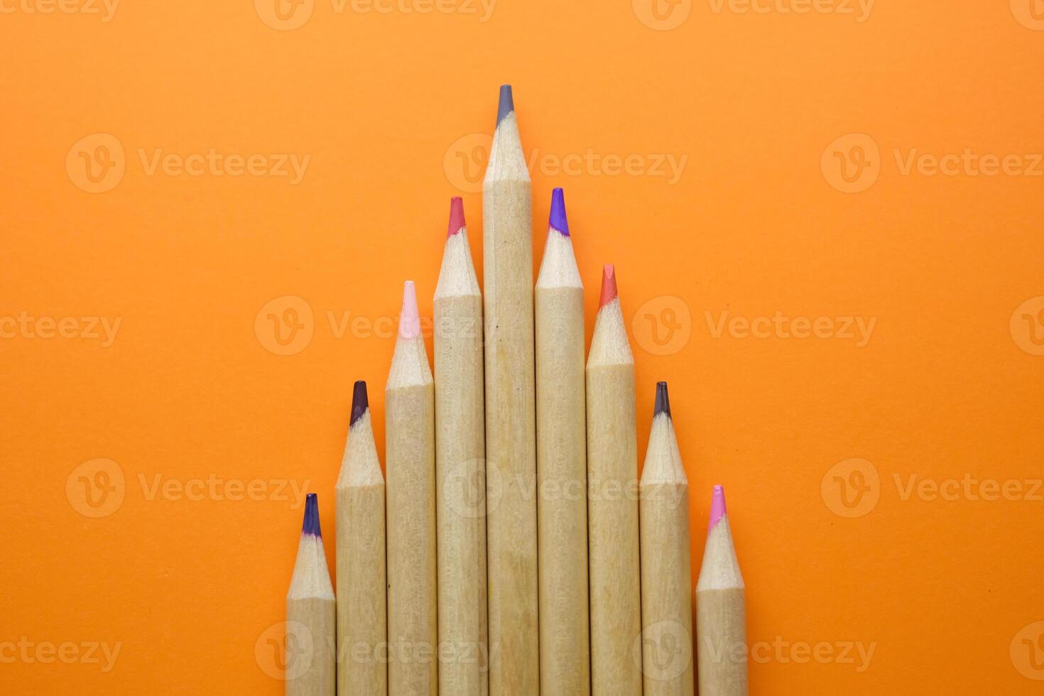 A Variety of Colorful Pencils Neatly Arranged in a Bright Pattern Set Against an Orange Background photo
