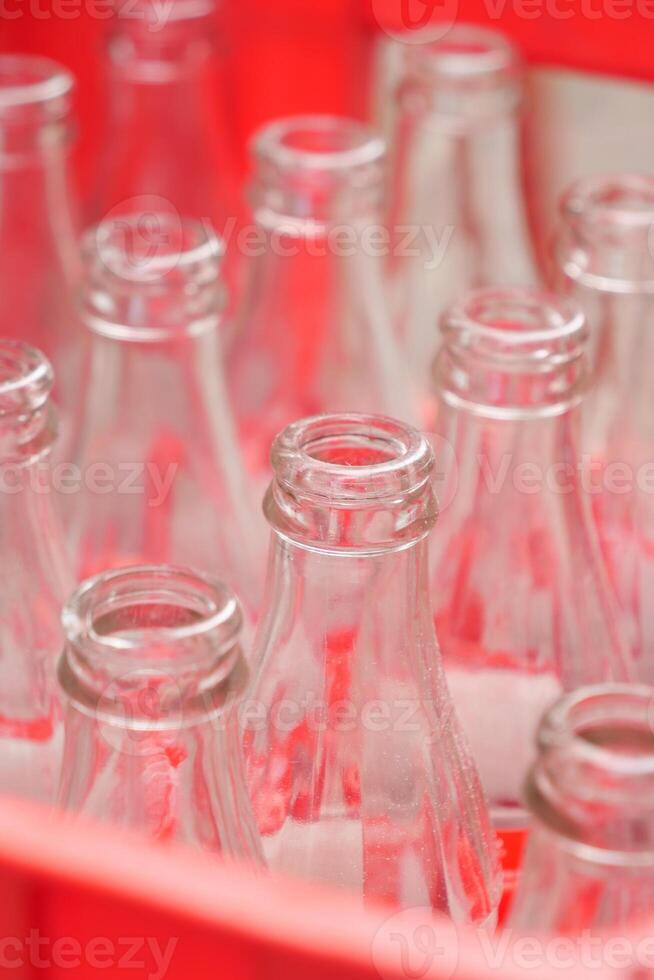 Empty glass bottles arranged in a vibrant red basket for storage and organization photo