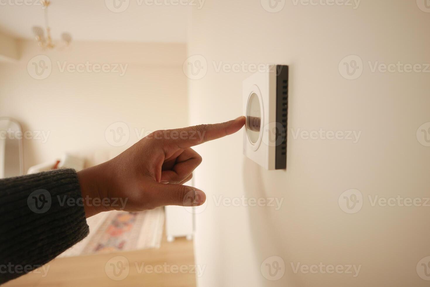 Hand Adjusting Smart Thermostat on White Wall for Optimal Home Temperature Control photo