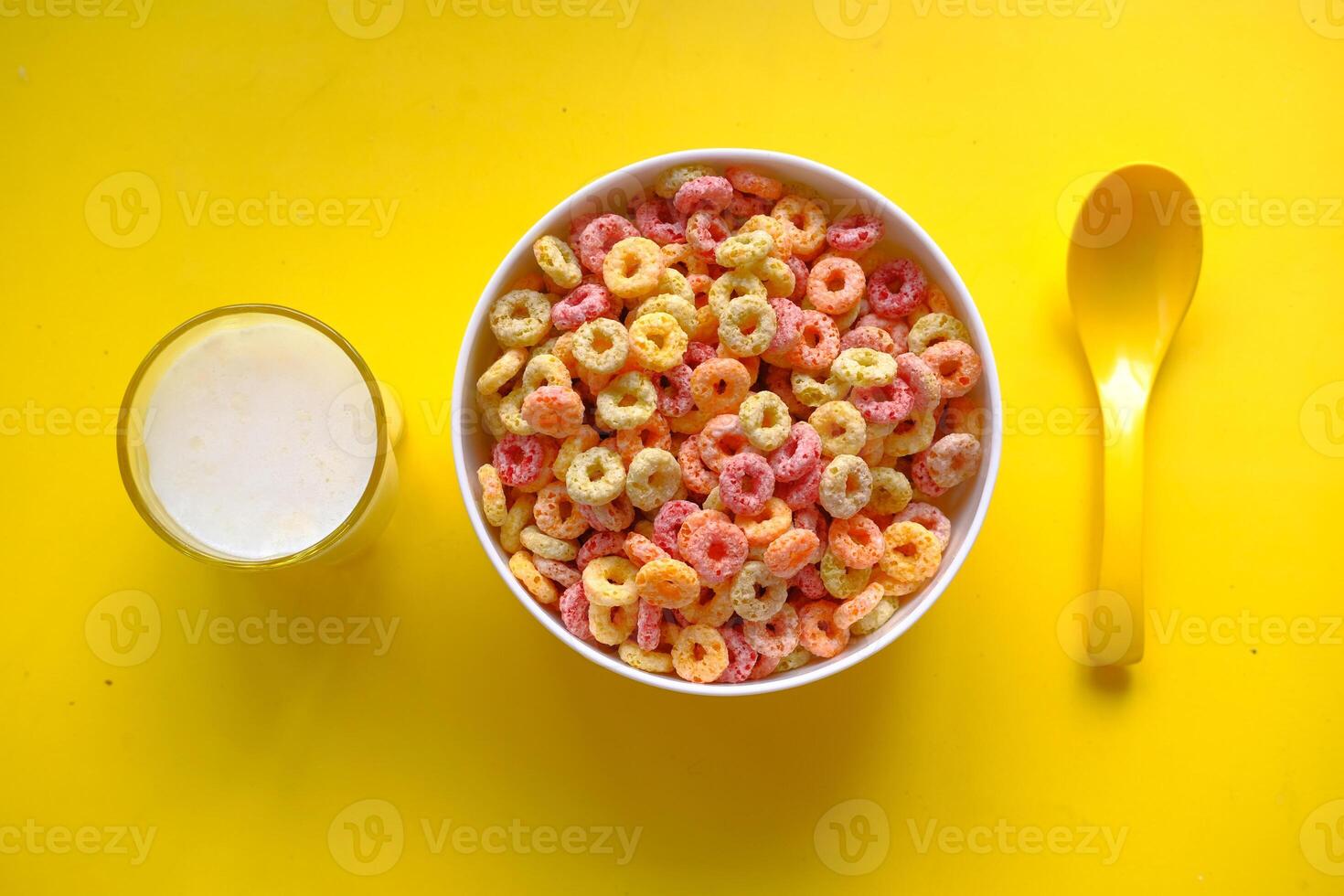 A Vibrant and Colorful Breakfast Cereal Served with Milk on a Bright Yellow Background photo