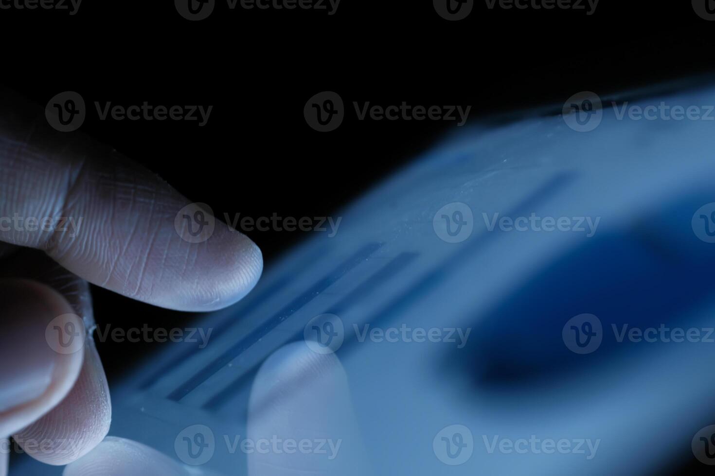 A closeup view of a finger engaging with a digital screen amidst a low light environment photo