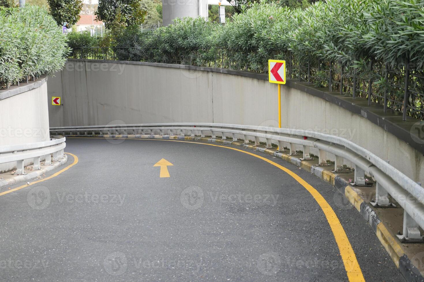 Curved Roadway Featuring Directional Signage Alongside a Sturdy Guardrail for Safety photo