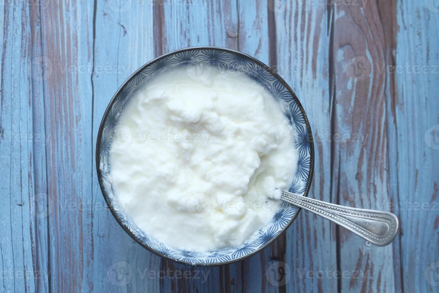 A Bowl of Creamy Yogurt with a Spoon Sitting Aesthetically on a Rustic Wooden Table photo