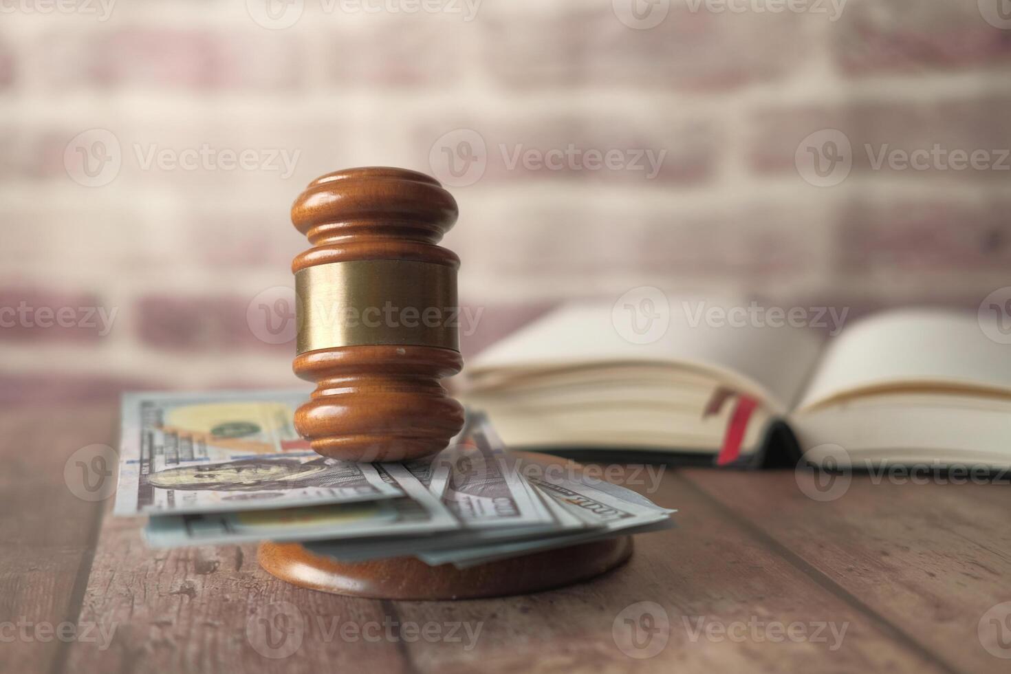 A judicial gavel placed upon a stack of money alongside an open law book for reference photo