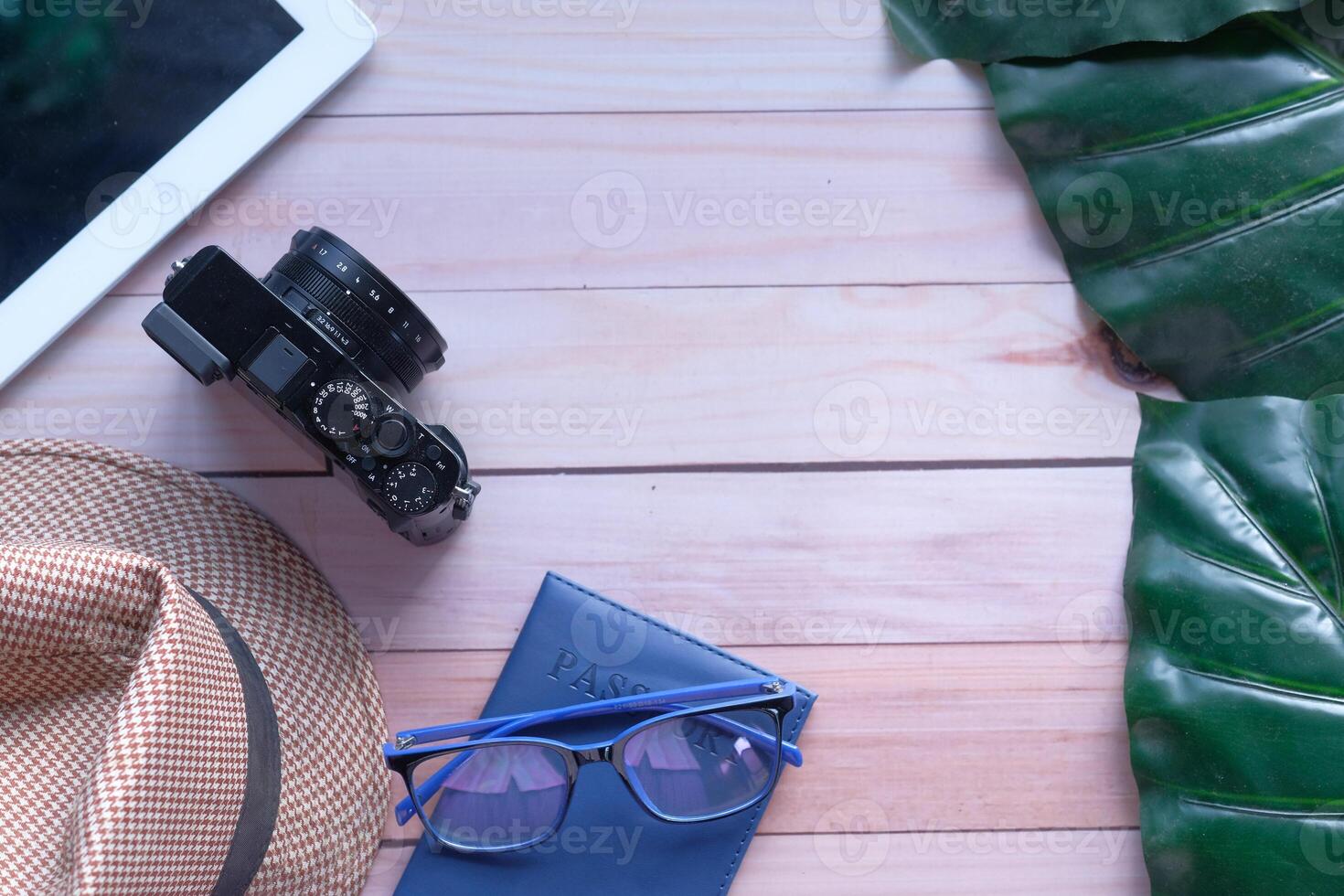 Essential Travel Items Displayed on a Wooden Table Including Camera, Sunglasses, and Hat photo