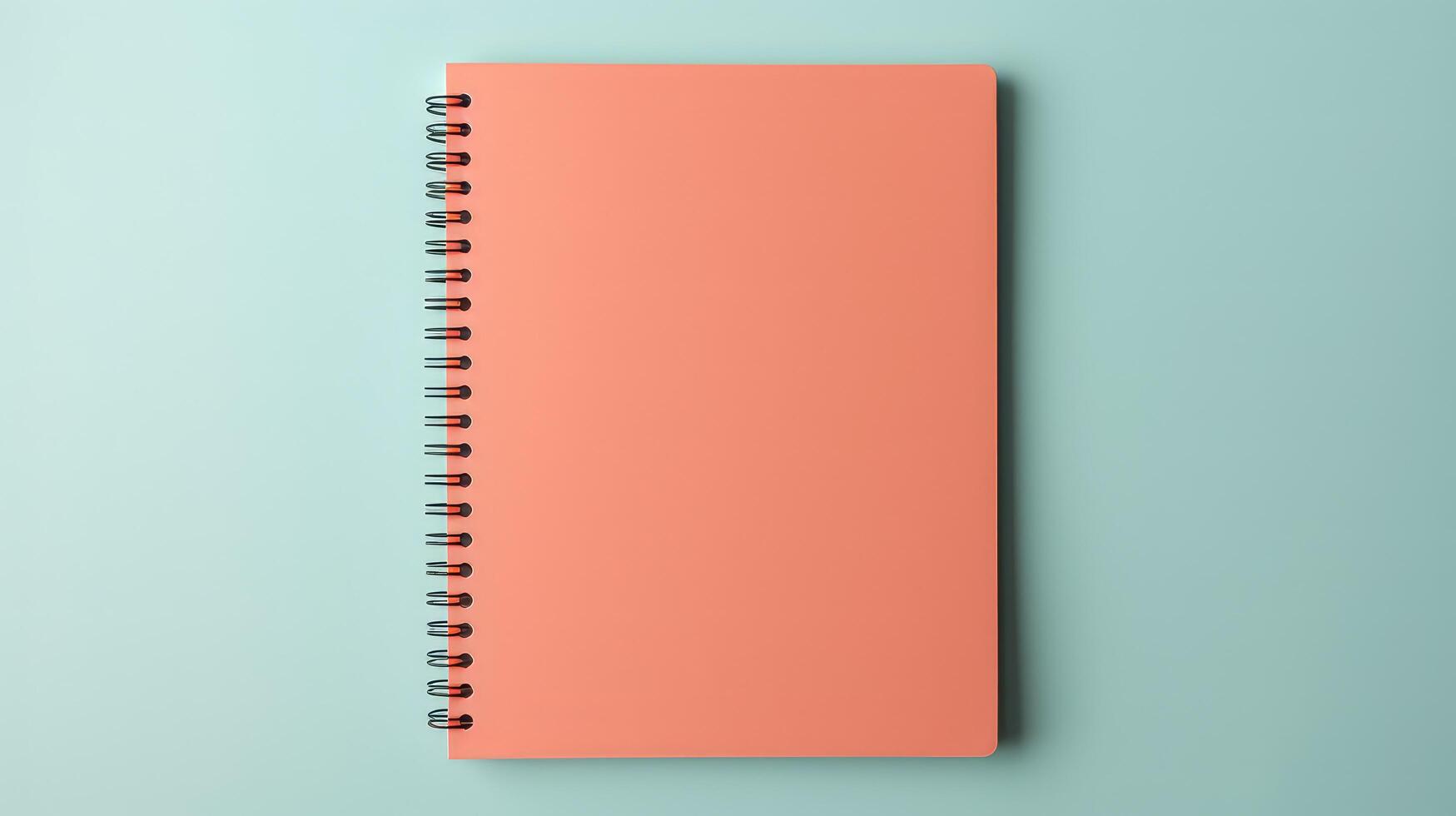 A pink spiral notebook sits on a blue background photo